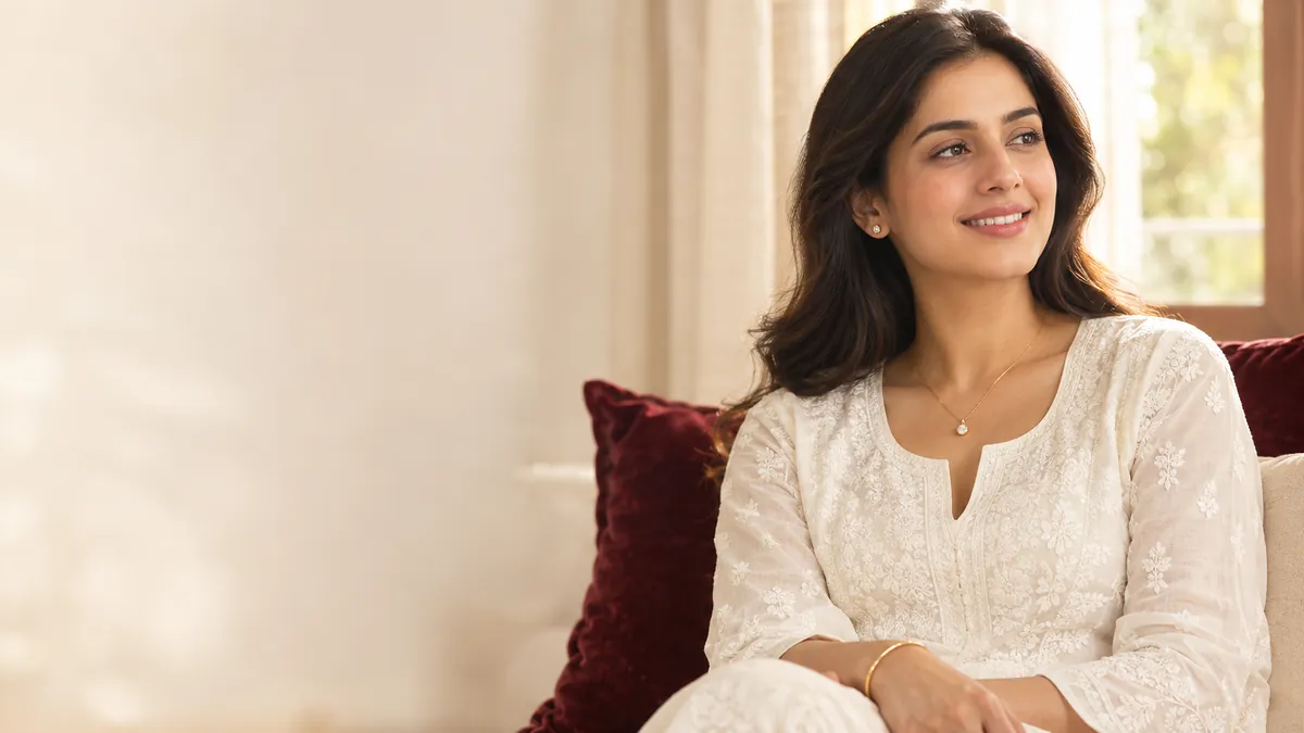 A woman in a white chikankari kurta wearing a fine gold chain, diamond studs and a thin gold bangle